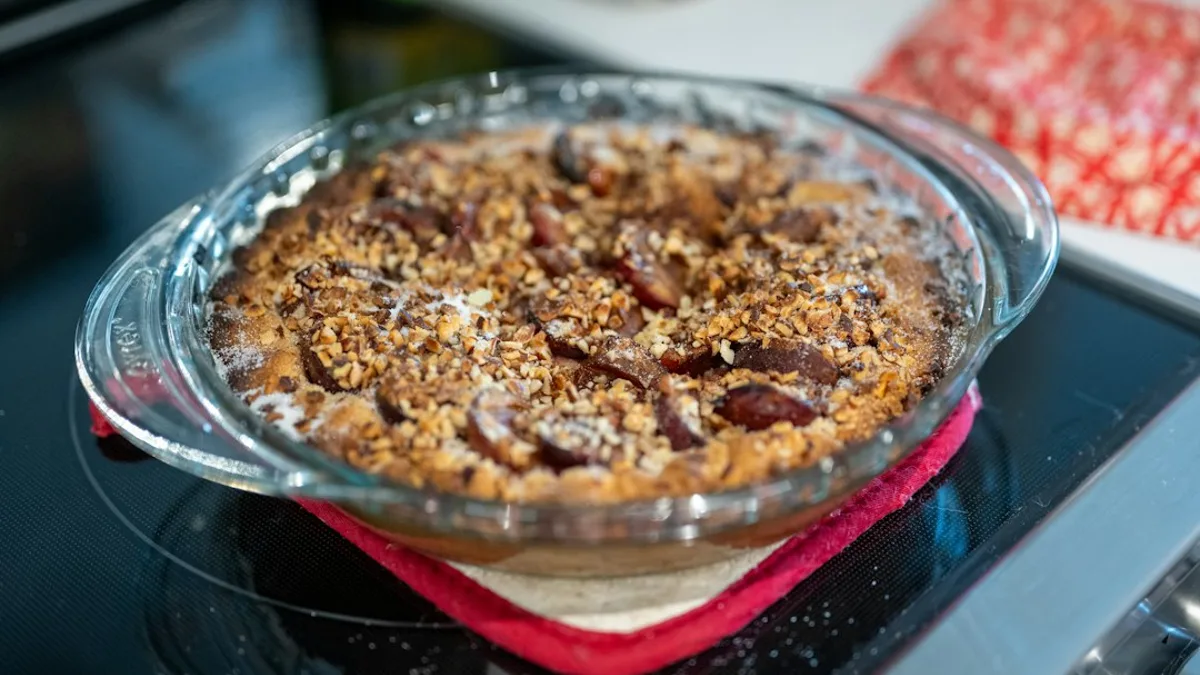 Clafoutis aux pommes doré dans un moule, tranches de pommes fondantes et surface saupoudrée de sucre glace.